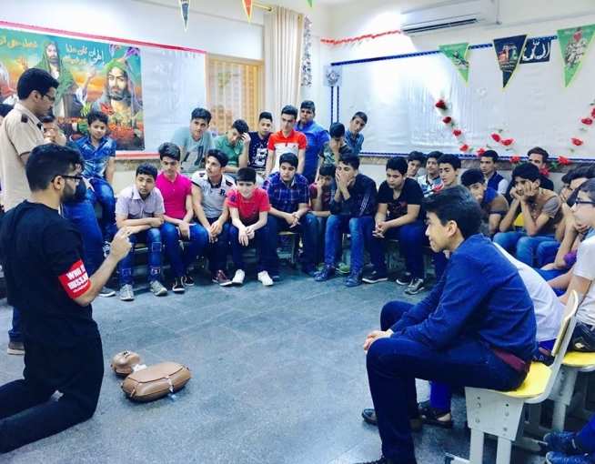 Mohammedabbas kneeling in front of a young audience, teaching basic life support techniques