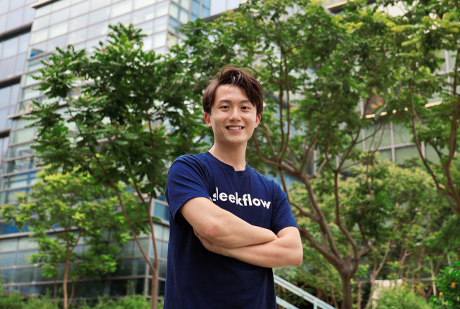 Photo of Henson Tsai standing with arms folded against backdrop of trees