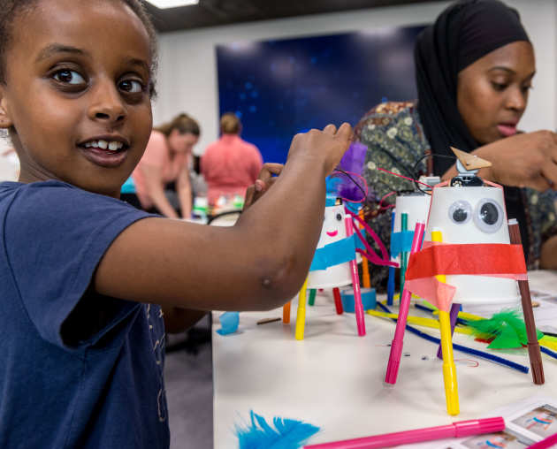 A young boy makes a robot out of straws and cups