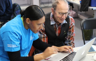 An Imperial student helps an elderly local resident with their laptop