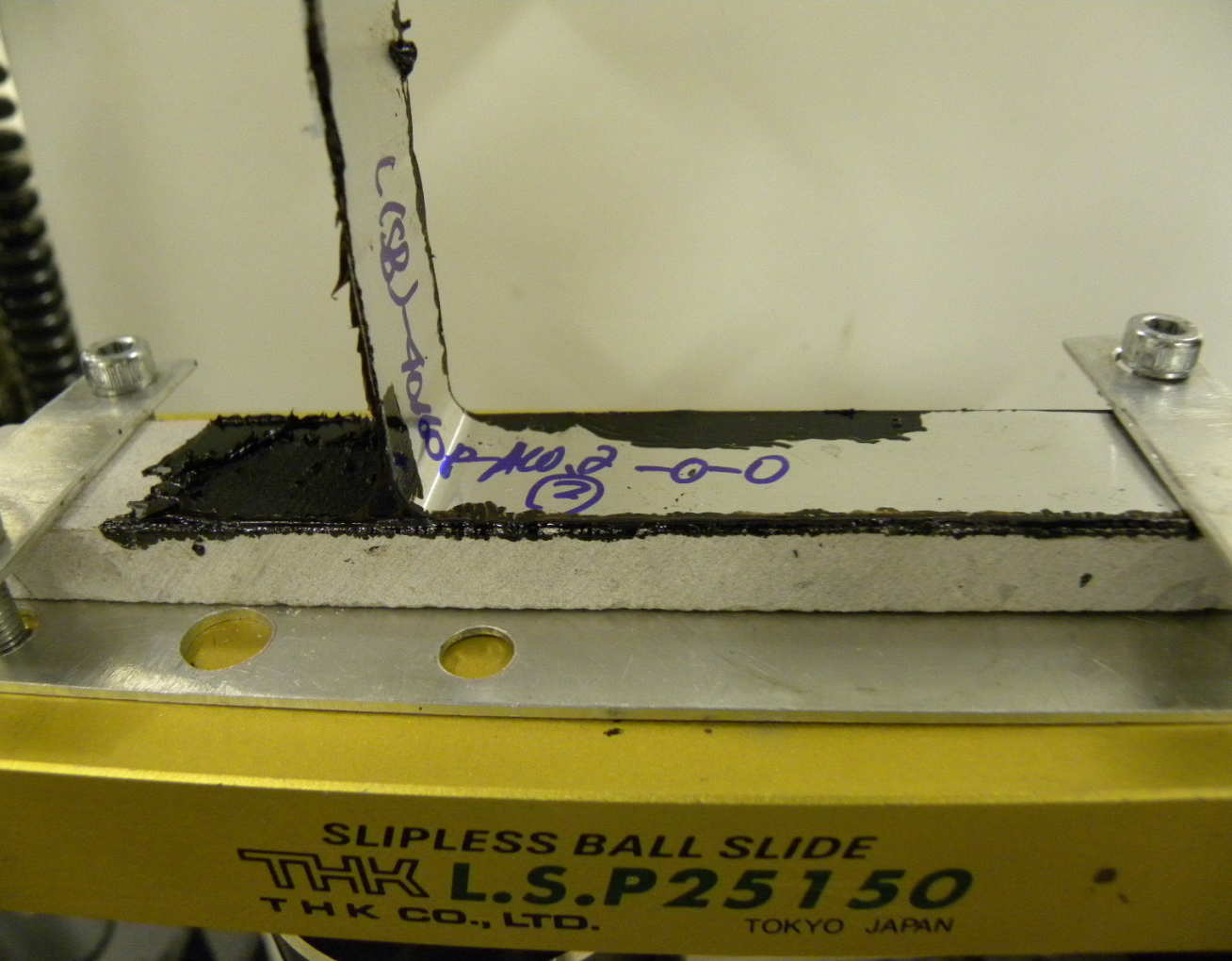 A flexible aluminium arm carrying the bitumen peeling in a peel test.  