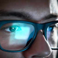 Person with computer screen reflected in glasses