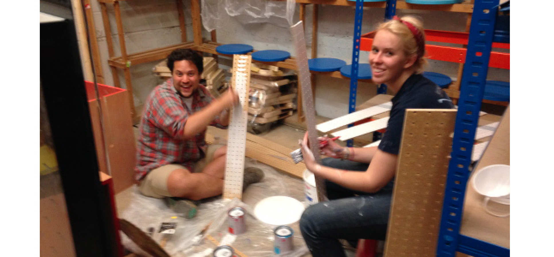 Two people paint shelves for shop