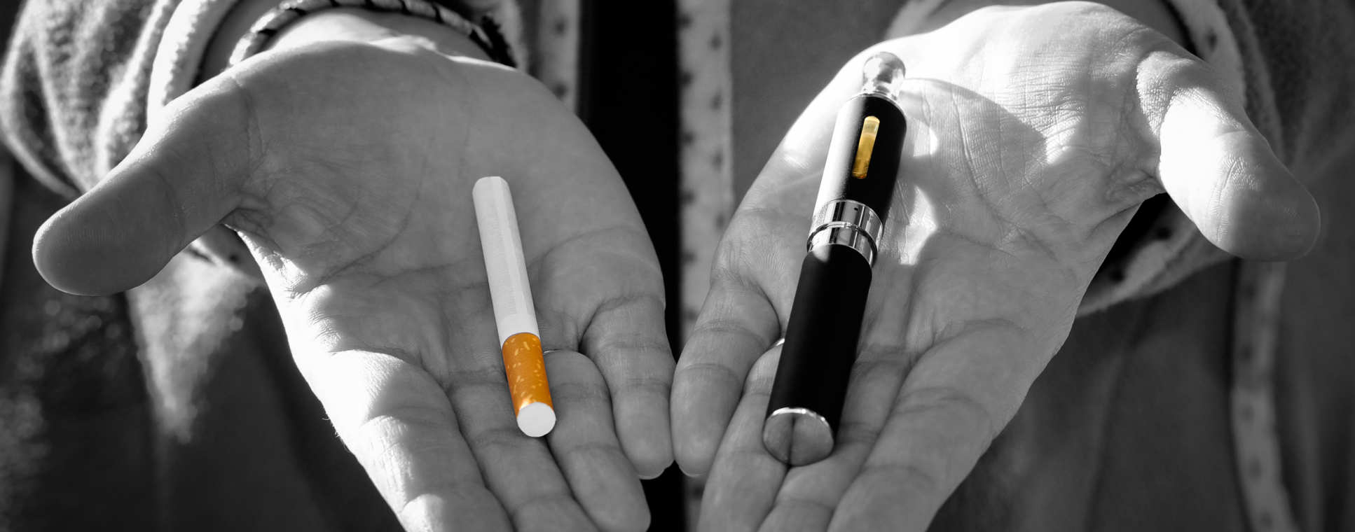 A pair of hands holding a cigarette and ecigarette