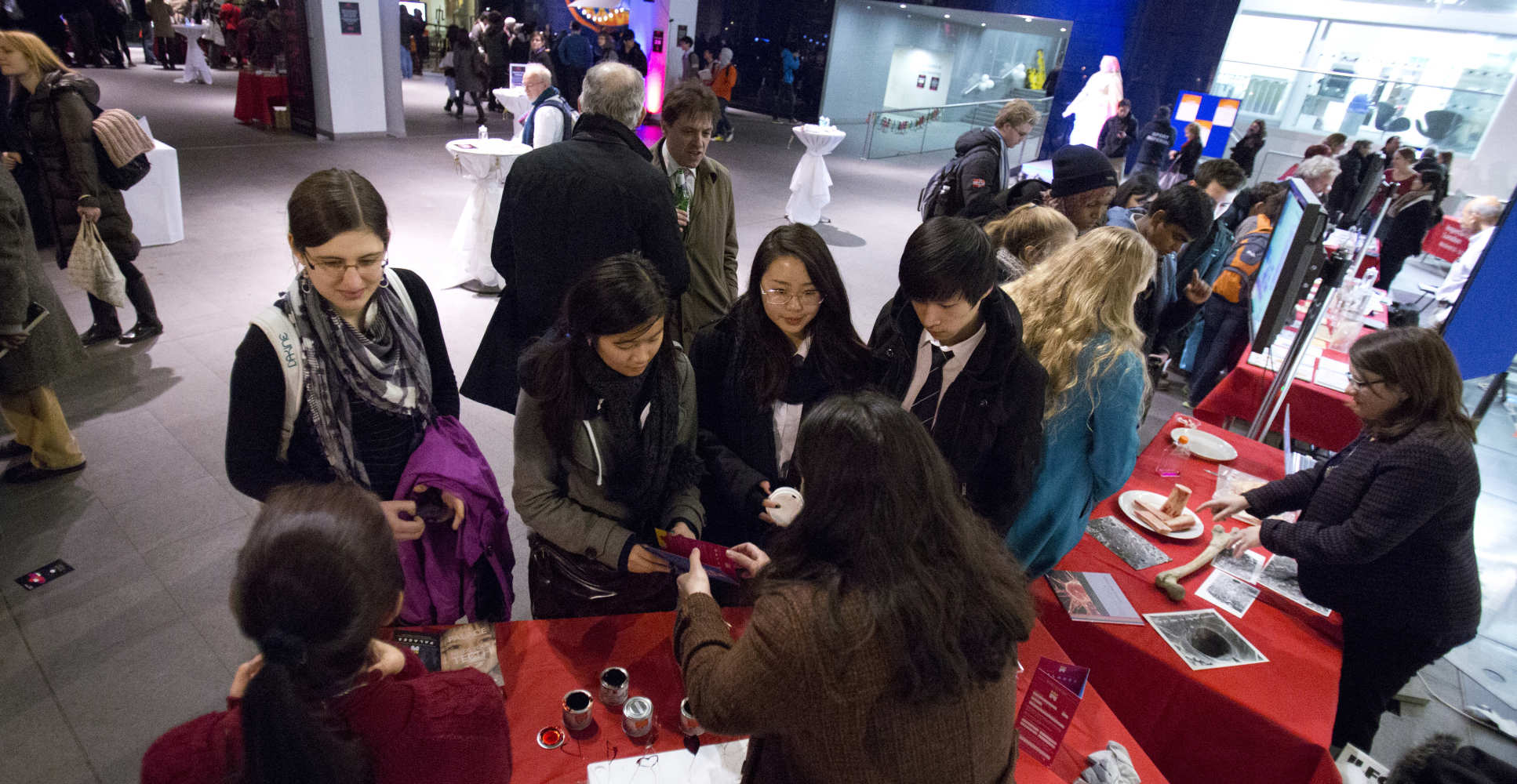 People gather round tables with information on