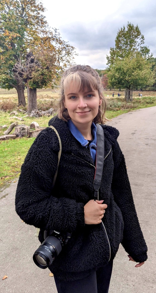 Charlotte McGinty stands outside holding a camera